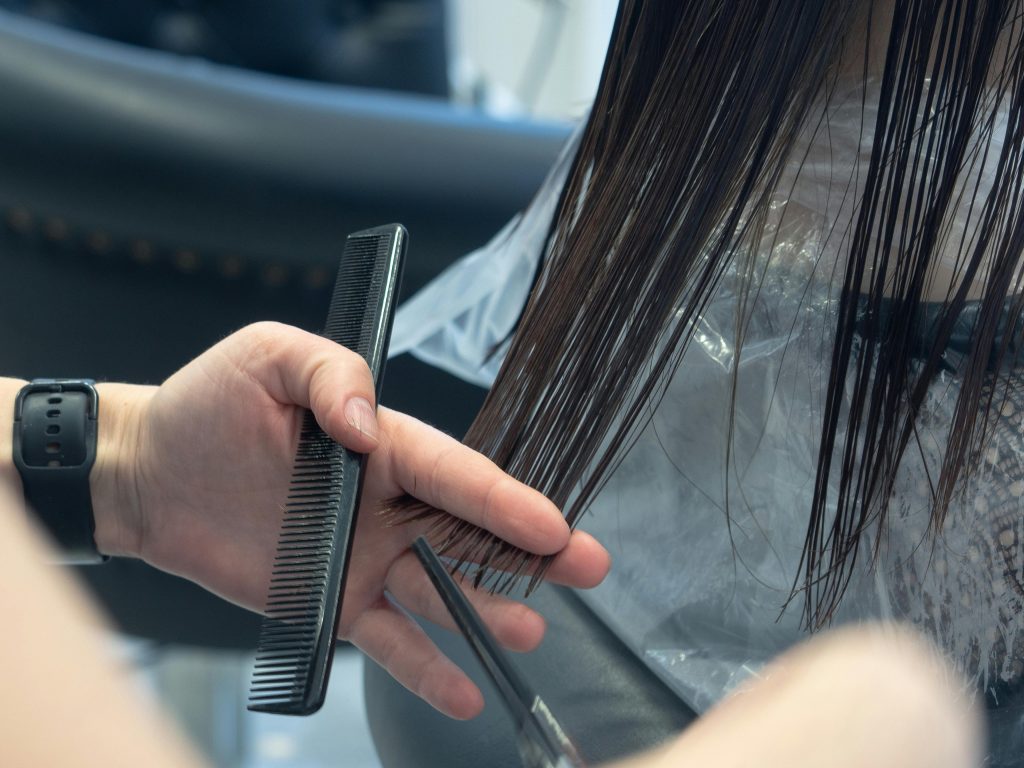 Close-up of a professional haircut in progress at a salon, highlighting comb and scissors.