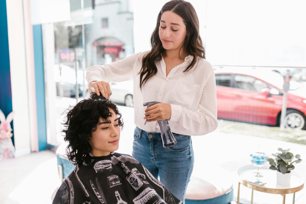 Hair stylist working on client's haircut with spray bottle in modern salon.